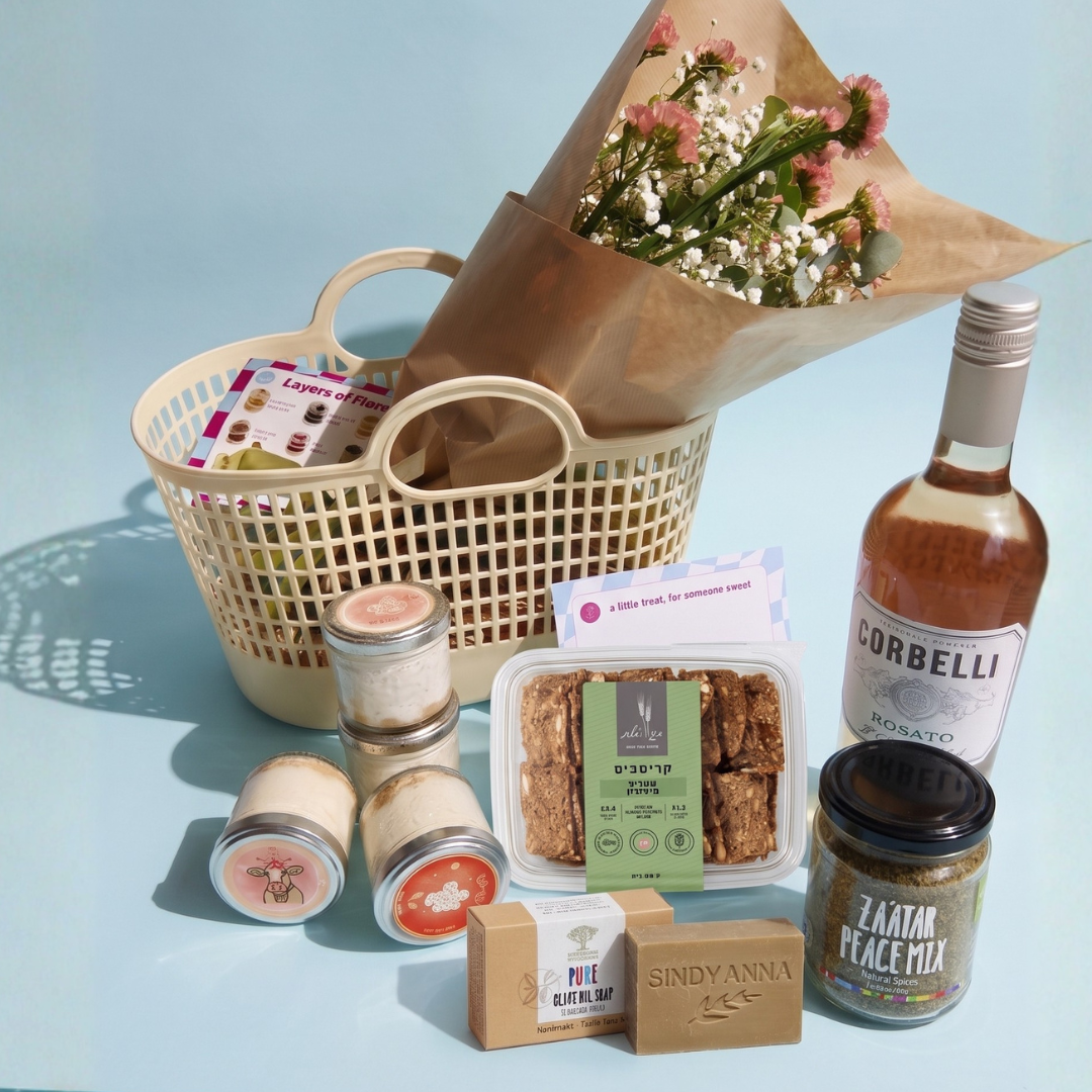 Gift basket with flowers, snacks, and a bottle on a light blue background